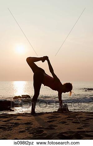 Woman practicing yoga on a beach at sunset View Large Photo Image Stock Photo - Woman practicing yoga on a beach at sunset. Fotosearch