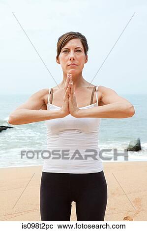 Stock Image - Woman practicing yoga on a beach. Fotosearch