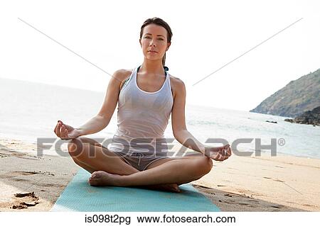 Stock Image - Woman practicing yoga on a beach. Fotosearch