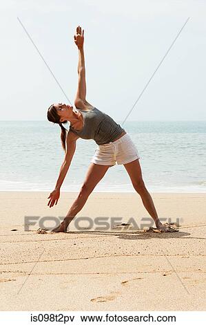 Stock Photo - Woman practicing yoga on a beach. Fotosearch