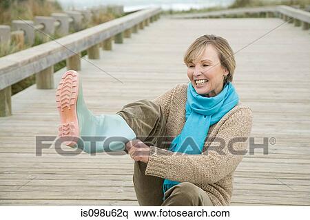 Woman putting on rubber boots View Large Photo Image Stock Photography - Woman putting on rubber boots. Fotosearch
