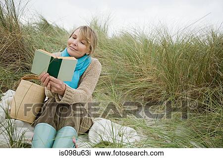 Woman reading a book on a dune View Large Photo Image Stock Image - Woman reading a book on a dune. Fotosearch