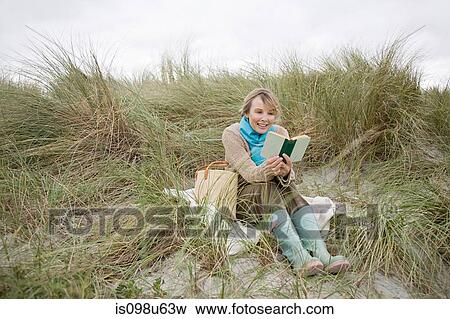 Woman reading a book on a dune View Large Photo Image Stock Photo - Woman reading a book on a dune. Fotosearch