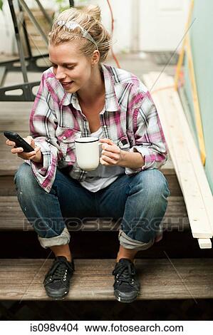 Picture - Woman sitting on steps with smartphone. Fotosearch