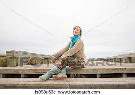 Woman sitting on walkway at the coast View Large Photo Image Stock Image - Woman sitting on walkway at the coast. Fotosearch