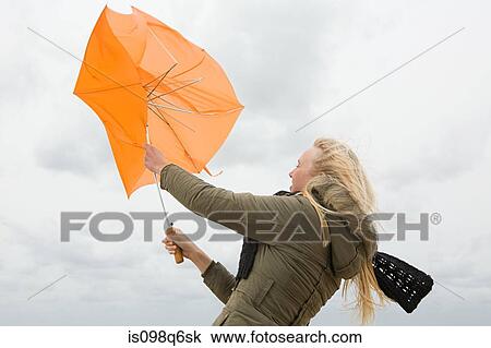 Stock Image - Woman struggling with umbrella. Fotosearch
