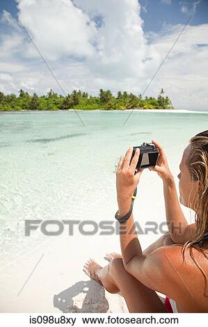 Stock Photo - Woman taking picture, Medahutthaa Island, North Huvadhu Atoll, Maldives. Fotosearch
