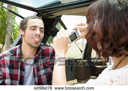 Woman taking picture of man sticking out tongue View Large Photo Image Stock Photo - Woman taking picture of man sticking out tongue. Fotosearch