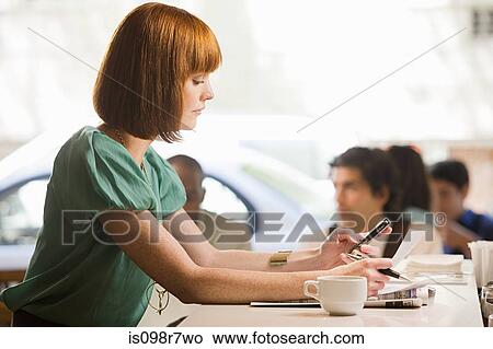 Woman using a cellular telephone in cafe View Large Photo Image Picture - Woman using a cellular telephone in cafe. Fotosearch