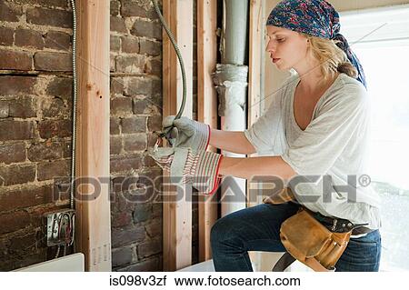 Stock Image - Woman wearing protective gloves working with wiring. Fotosearch