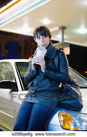 Stock Image - Woman with drink at petrol station. Fotosearch