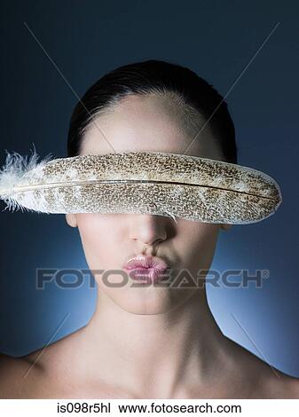 Stock Image - Woman with feather over eyes. Fotosearch