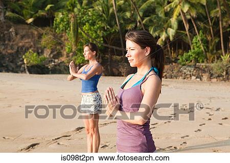 Picture - Women practicing yoga on a beach. Fotosearch