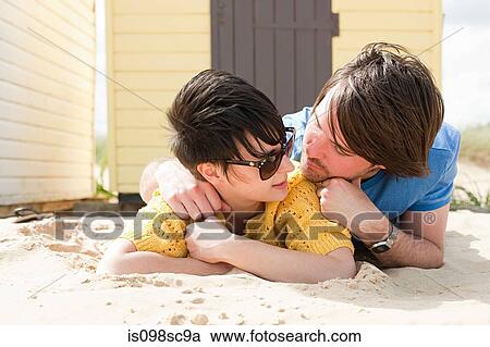 Stock Image - Young couple by a beach hut. Fotosearch