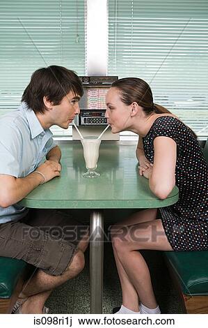 Stock Image - Young couple drinking a milkshake. Fotosearch