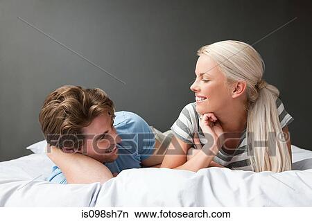 Picture - Young couple lying on bed. Fotosearch