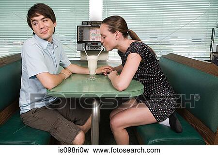 Young couple sharing a milkshake View Large Photo Image Stock Photo - Young couple sharing a milkshake. Fotosearch