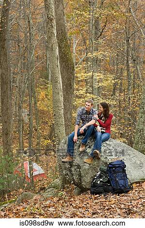 Young couple sitting on boulder in forest View Large Photo Image Stock Photo - Young couple sitting on boulder in forest. Fotosearch