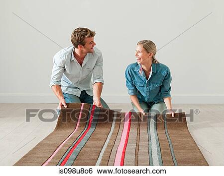 Young couple unrolling rug on floor View Large Photo Image Stock Photograph - Young couple unrolling rug on floor. Fotosearch