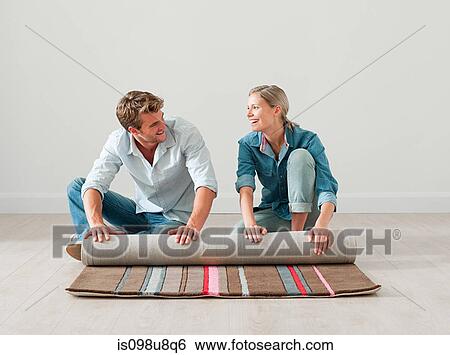 Young couple unrolling rug on floor View Large Photo Image Stock Photograph - Young couple unrolling rug on floor. Fotosearch
