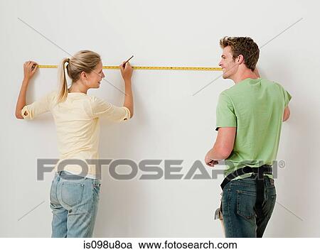 Young couple using measuring tape on wall View Large Photo Image Stock Image - Young couple using measuring tape on wall. Fotosearch