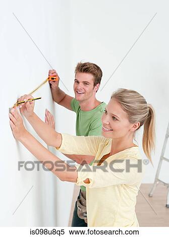 Young couple using measuring tape on wall View Large Photo Image Stock Photography - Young couple using measuring tape on wall. Fotosearch
