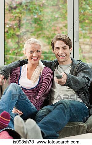 Young couple watching television View Large Photo Image Stock Photo - Young couple watching television. Fotosearch