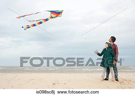 Stock Image - Young couple with kite by the sea. Fotosearch