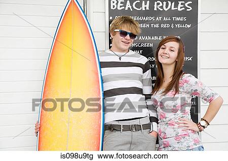 Stock Image - Young couple with surfboard, portrait. Fotosearch