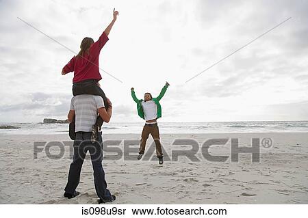 Stock Photography - Young man carrying girl on shoulders on beach. Fotosearch