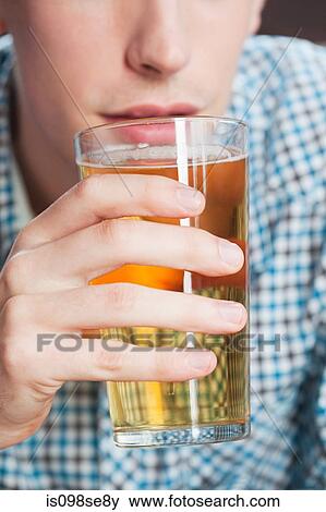 Stock Photo - Young man drinking beer, close up. Fotosearch