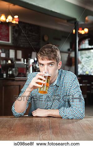 Stock Image - Young man drinking beer. Fotosearch