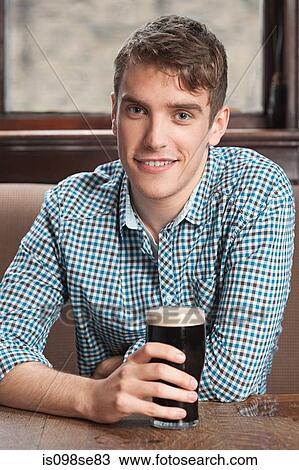 Young man in bar View Large Photo Image Stock Image - Young man in bar. Fotosearch