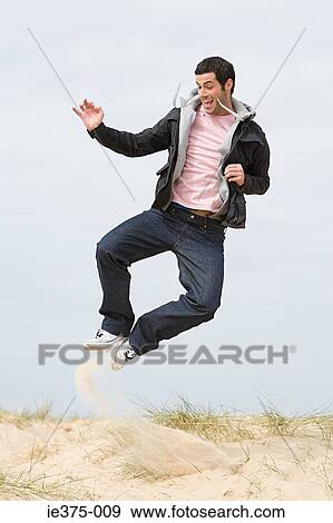 Stock Photo - Young man jumping on a beach. Fotosearch
