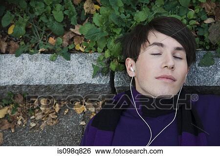 Young man lying on floor listening to music View Large Photo Image Stock Photograph - Young man lying on floor listening to music. Fotosearch