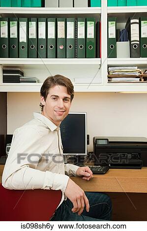 Stock Photo - Young man sitting in home office. Fotosearch