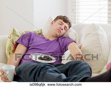 Young man sleeping on a sofa View Large Photo Image Stock Image - Young man sleeping on a sofa. Fotosearch