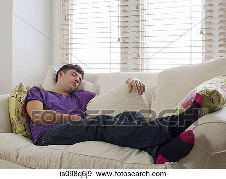 Young man sleeping on a sofa View Large Photo Image Stock Photo - Young man sleeping on a sofa. Fotosearch