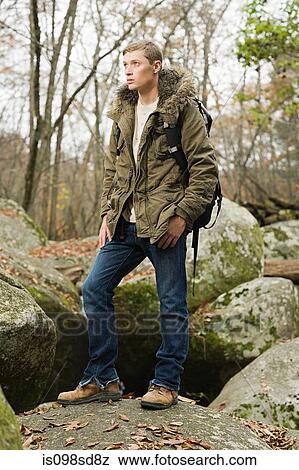Young man standing on stones in forest View Large Photo Image Stock Photo - Young man standing on stones in forest. Fotosearch