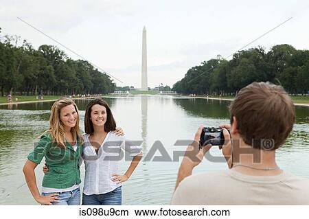 Young man taking photograph of friends at washington monument View Large Photo Image Picture - Young man taking photograph of friends at washington monument. Fotosearch