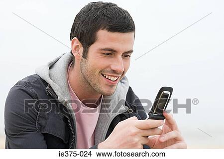 Picture - Young man using a cellular telephone. Fotosearch