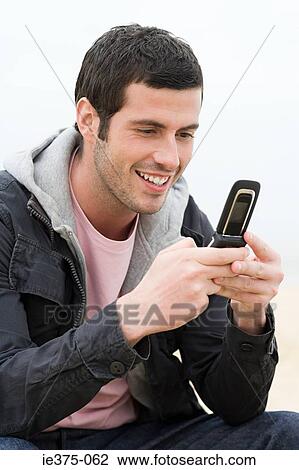 Stock Image - Young man using a cellular telephone. Fotosearch