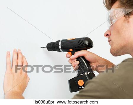 Young man using electric drill View Large Photo Image Stock Photography - Young man using electric drill. Fotosearch