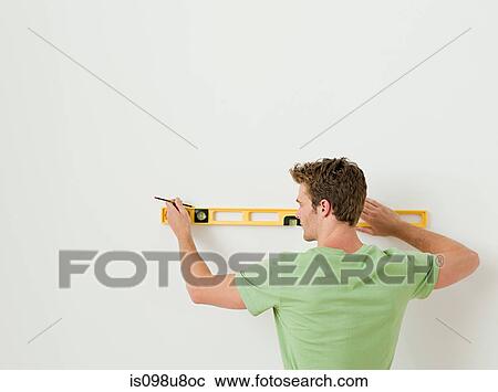 Young man using spirit level on wall View Large Photo Image Stock Image - Young man using spirit level on wall. Fotosearch