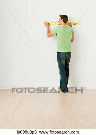 Young man using spirit level on wall View Large Photo Image Stock Image - Young man using spirit level on wall. Fotosearch