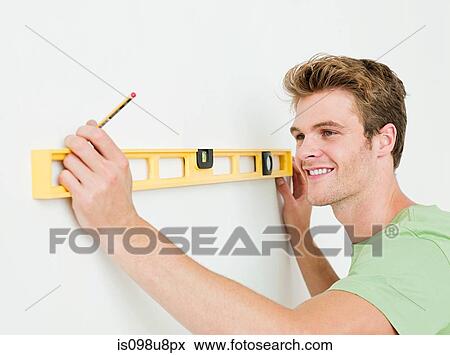 Young man using spirit level on wall View Large Photo Image Stock Photo - Young man using spirit level on wall. Fotosearch