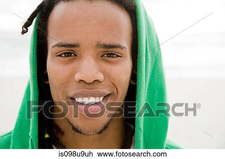 Stock Image - Young man with green hooded top, portrait. Fotosearch