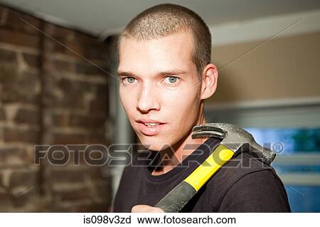 Stock Image - Young man with hammer, portrait. Fotosearch