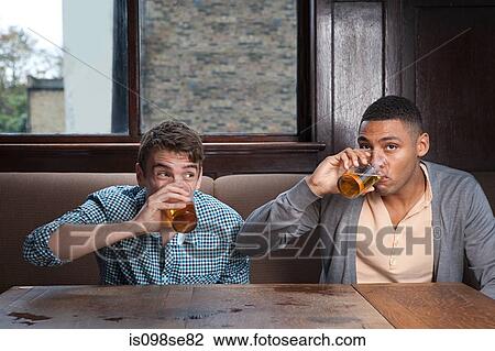 Stock Image - Young men drinking beer in bar. Fotosearch