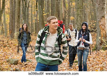 Young people hiking through forest View Large Photo Image Stock Image - Young people hiking through forest. Fotosearch